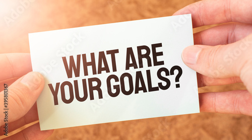 What Are Your Goals word inscription on white card paper sheet in hands of a businessman. recap concept. red and white paper