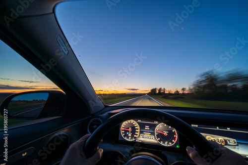 Movement of the car at night at high speed view from the interior with driver hands on wheel. Concept speed of life.