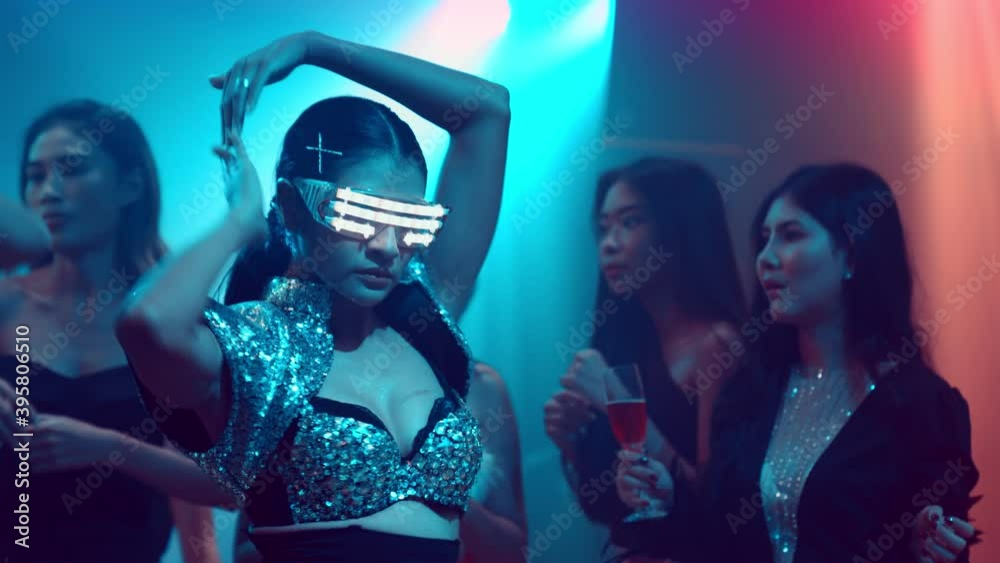 Group of people dance in disco night club to the beat of music from DJ on stage . New year night party and nightlife concept .