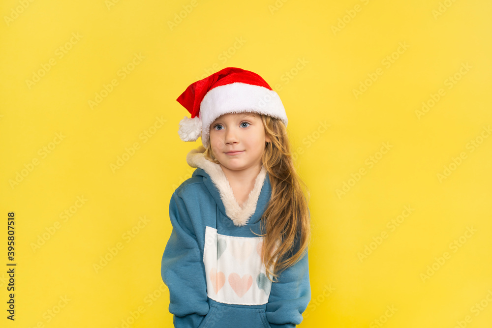 Little beautiful girl in santa hat smiling isolated on yellow background Little beautiful girl in santa hat smiling isolated on yellow background