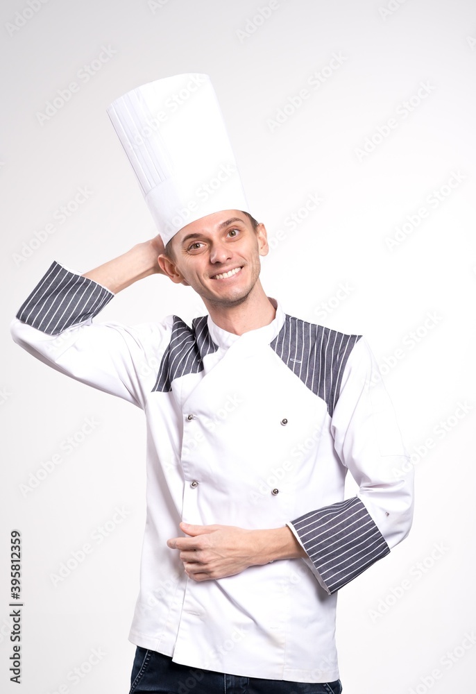 Pleased happy young chef posing isolated over white wall background in uniform. Pleased happy young chef posing isolated over white wall background in uniform.