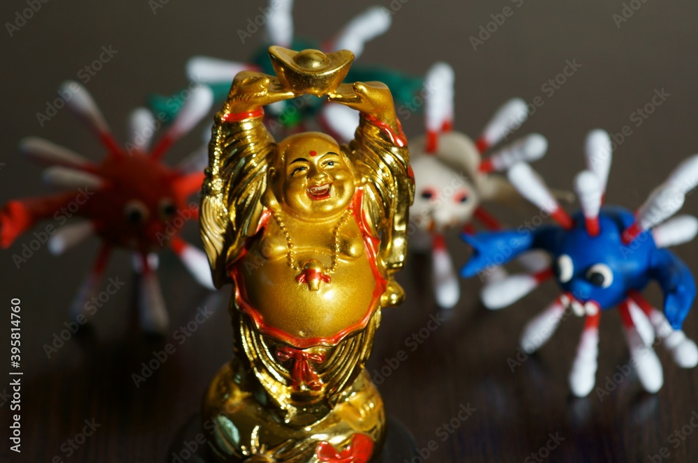 Small Buddha statue on the table. There are virus figures in the background.