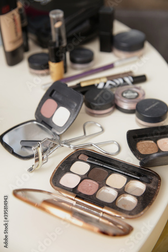 Different types of makeup shadows and makeup equipment on the white table.