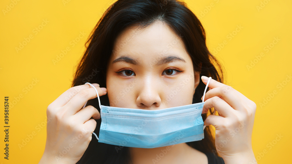 Young asian woman putting on medical mask. Close up. Prevention of the covid-19 spread. High quality photo