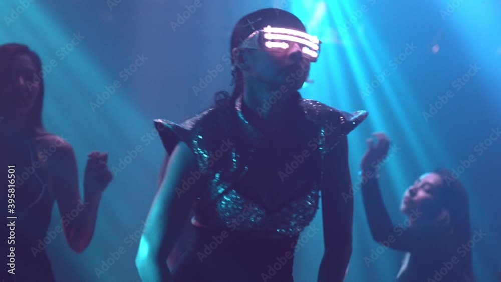 Group of people dance in disco night club to the beat of music from DJ on stage . New year night party and nightlife concept .