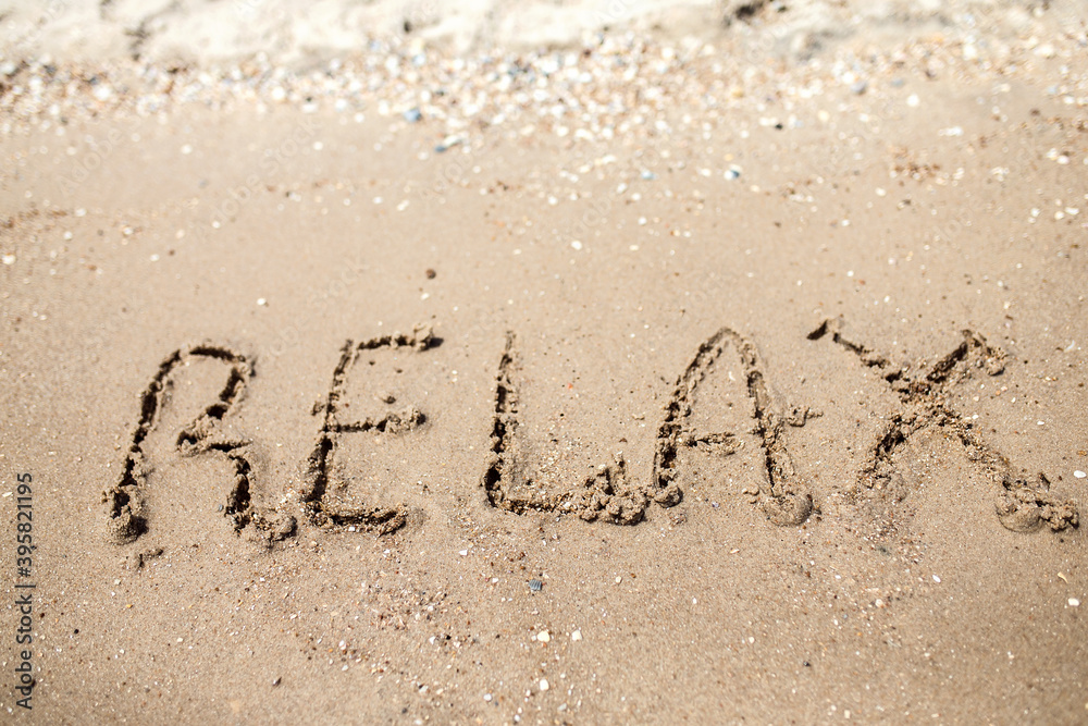 Fototapeta premium Handwritten Relax Word on the Sand Coast. Wonderful words on beach sand. Love idea concept.