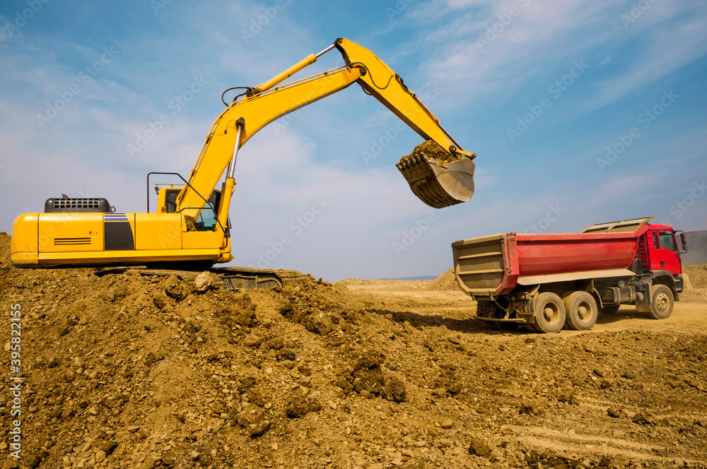 Earthworks on a summer day in a mountainous area. Excavators load soil into the tipper body Earthworks on a summer day in a mountainous area. Excavators load soil into the tipper body