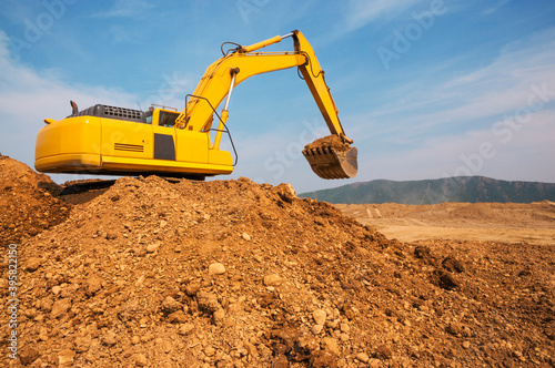 The excavator has scooped up a bucket of earth and is awaiting the arrival of a dump truck