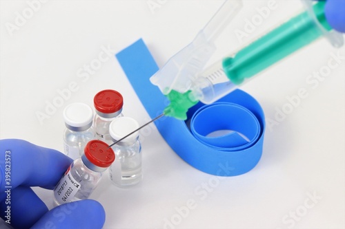 vacuna cargando viales con guantes azules, jeringa y compresor con fondo blanco