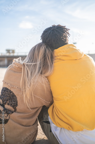 Black Afro blonde woman in a park in the sun wearing yellow sweater and jacket