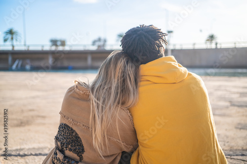 Black Afro blonde woman in a park in the sun wearing yellow sweater and jacket