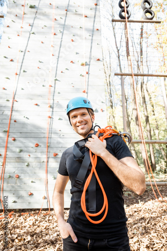 Portrait of a happy man well equipped with protective climbing equipment at amusement park outdoors