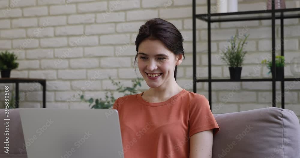 Head shot smiling european millennial woman looking at laptop screen, reading pleasant email news or enjoying communicating online with friends in social networks, relaxing on sofa alone at home. Head shot smiling european millennial woman looking at laptop screen, reading pleasant email news or enjoying communicating online with friends in social networks, relaxing on sofa alone at home.