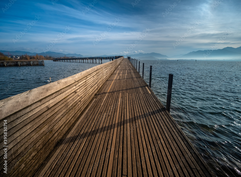 Fototapeta premium Stunning views of the historic wood bridge (Holzsteg) connecting the village of Hurden, Seedam, Schwyz with the city of Rapperswil, St. Gallen