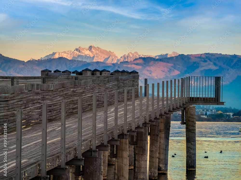 Stunning views of the historic wood bridge (Holzsteg) crossing the Zurich Lake with the Santis mountain peak in the background, Switzerland