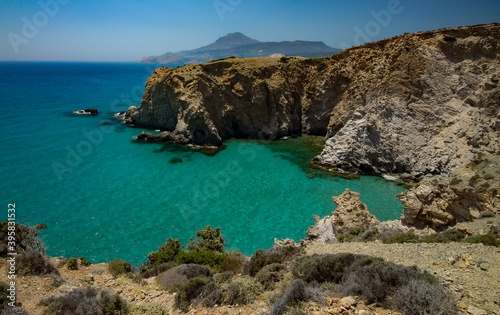 Jagged cliffs plunge into the turquoise waters of the Mediterranean Sea at Tsigrado beach, Milos, Greece