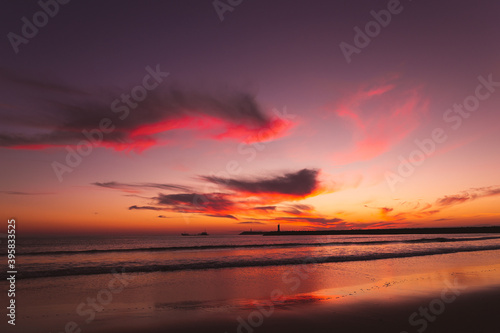sunset on the beach in the Atlantic ocean Viana do Castelo Praia do Cabedelo Cabedelo beach colorful clouds with a lighthouse © Nauris