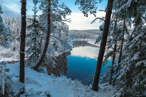 Gaujas National park Latvia Gauja river Erglu Cliffs sandstone walls snow covered trees in the winter reflection mirror nor frozen river photo