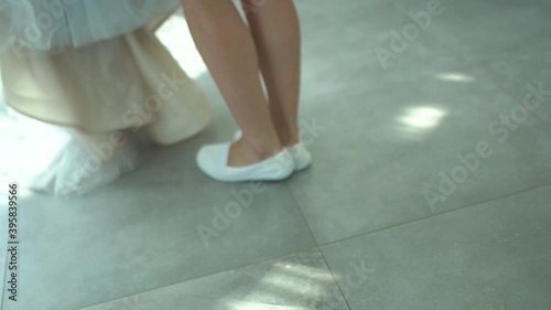 the woman comes up to the wedding dress and stands on tiptoe to remove it from the hanger photo