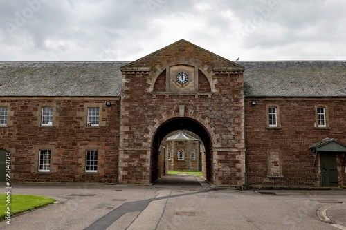 Canvas Print Red brick barracks with a arch gate and clock in historical Fort George complex