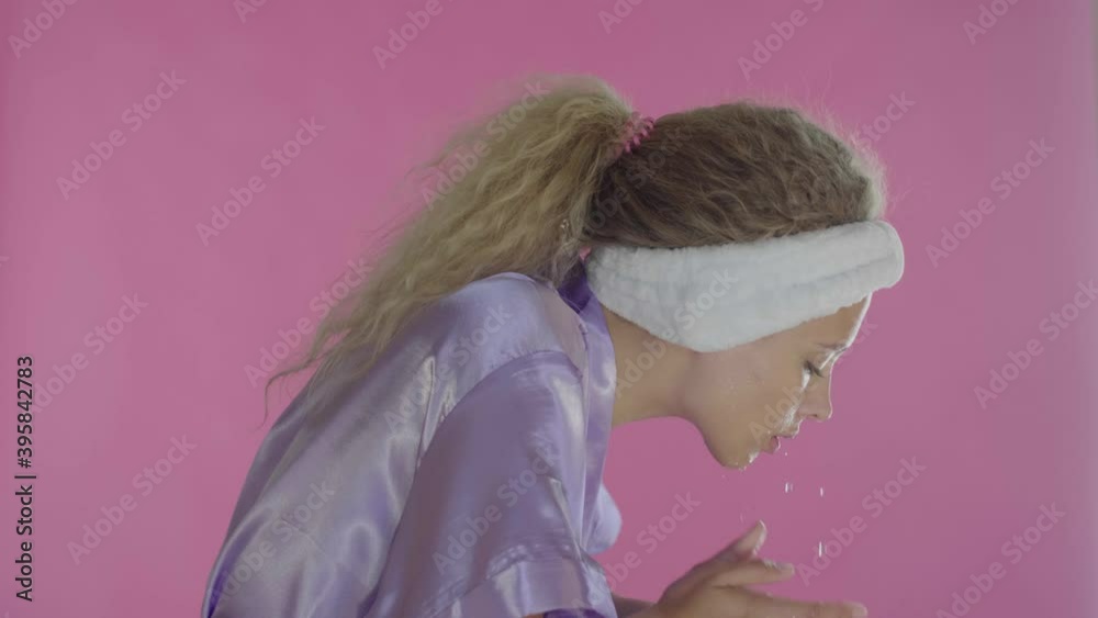 Young woman in white bathrobe washing face with clean water at morning Young woman in white bathrobe washing face with clean water at morning