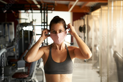 Young woman with sportswear with face mask looking at camera in gym. © CarlosBarquero