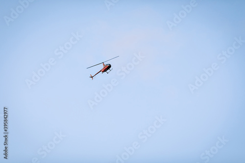 Fototapeta Naklejka Na Ścianę i Meble -  Silhouette of a chopper high in the blue sky seen from below, the military maneuvers; worm’s eye view.
