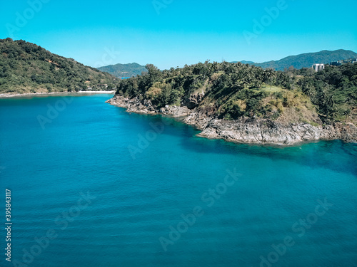 Drone view of the lagoon: narrow strip of the white sand, clear blue water and green hills covered with tropical forest; paradise concept.