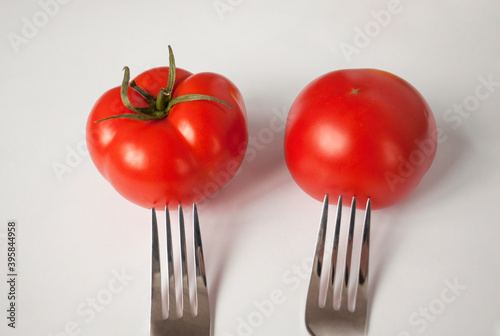 Two ripe red tomatoes on a fork on a light background. Healthy Eating