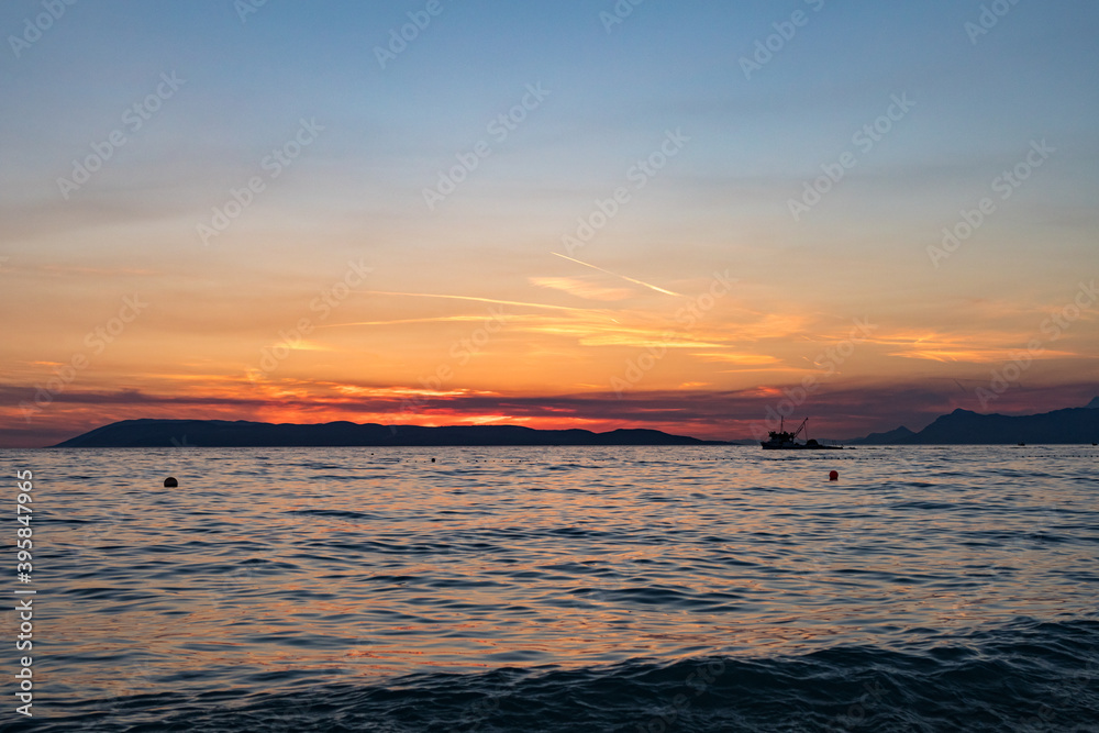 Sonnenuntergang an der Küste in Tučepi in Kroatien. Blick auf das Meer, die Wellen, die Insel Brač am Horizont