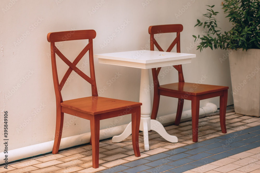 Fototapeta premium Two wooden brown chairs are next to a snow-white table in a light-colored house