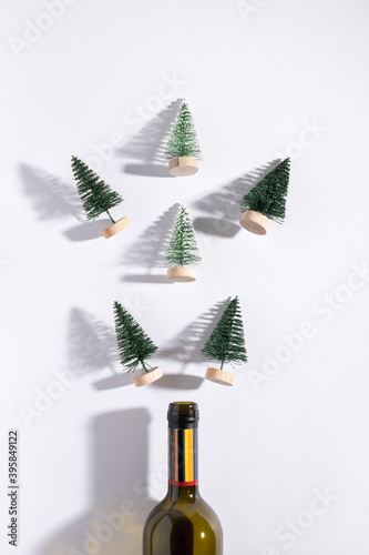 Champagne bottle with Christmas trees on white background. Flat lay. Minimal party concept.