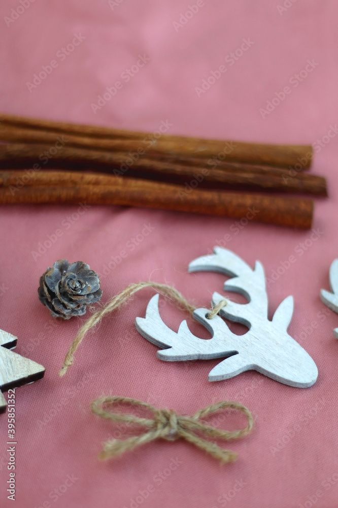 Various Christmas decorations and cinnamon sticks on pink background. Selective focus.