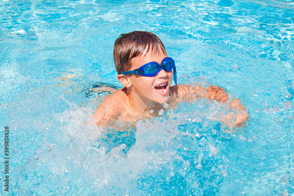 Happy boy in a swimming pool. Cute little kid boy having fun in a swimming pool. Outdoors. Sport activities for children.