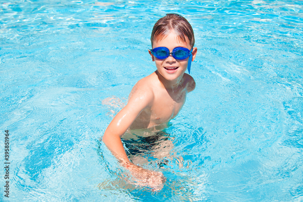 Naklejka premium Happy boy in a swimming pool. Cute little kid boy having fun in a swimming pool. Outdoors. Sport activities for children.