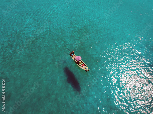 A lonely boat is floating peacefully in the middle of a vast blue ocean, aerial view