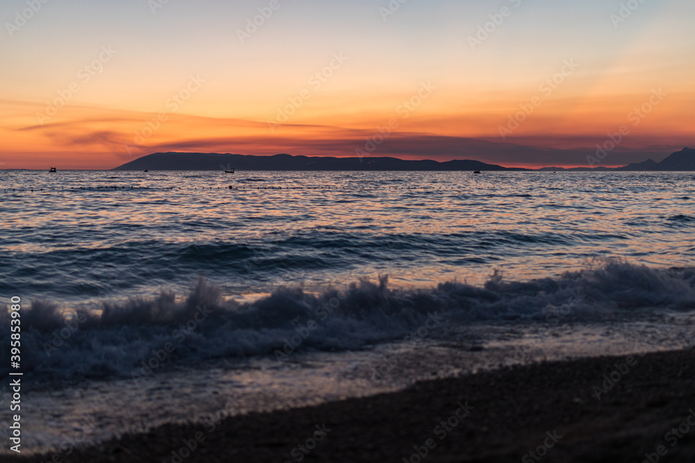 Sonnenuntergang an der Küste in Tučepi in Kroatien. Blick auf das Meer, die Wellen, die Insel Brač und die Berge