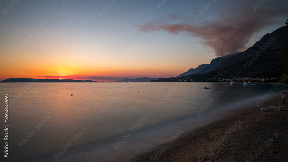 Sonnenuntergang an der Küste in Tučepi in Kroatien. Blick auf das Meer, Rauch, Wellen, Insel Brač und die Berge, Panorama