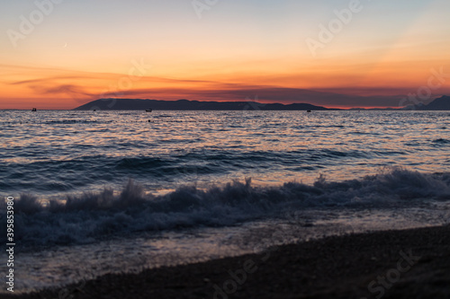 Sonnenuntergang an der Küste in Tučepi in Kroatien. Blick auf das Meer, die Wellen, die Insel Brač und die Berge
