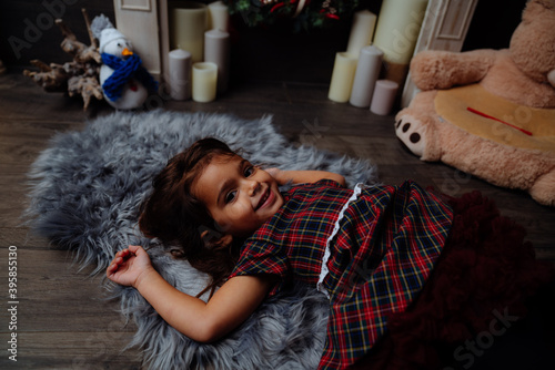 little baby girl with tartan dress smiling and happy lying on a gray fur