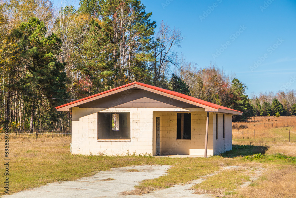 Abandoned block building with a red roof in the country and blue skies