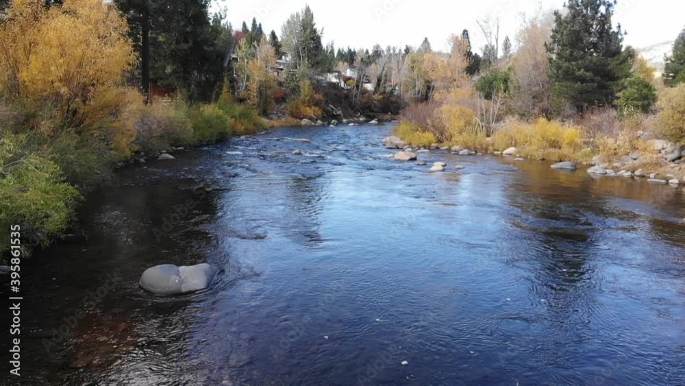 Water flowing downstream in slow motion with red orange and yellow trees on the banks. Water flowing downstream in slow motion with red orange and yellow trees on the banks.