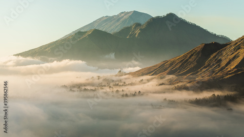 Sunrise view of mount Batur, Abang and Agung volcano in Bali from Pinggan village. Beautiful sunrise and low clouds. Layered minimalist landscape. photo