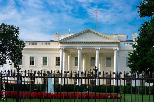 view of the White House, presidential residence in Washington DC with red flowers, grass and fountains behind security fencing