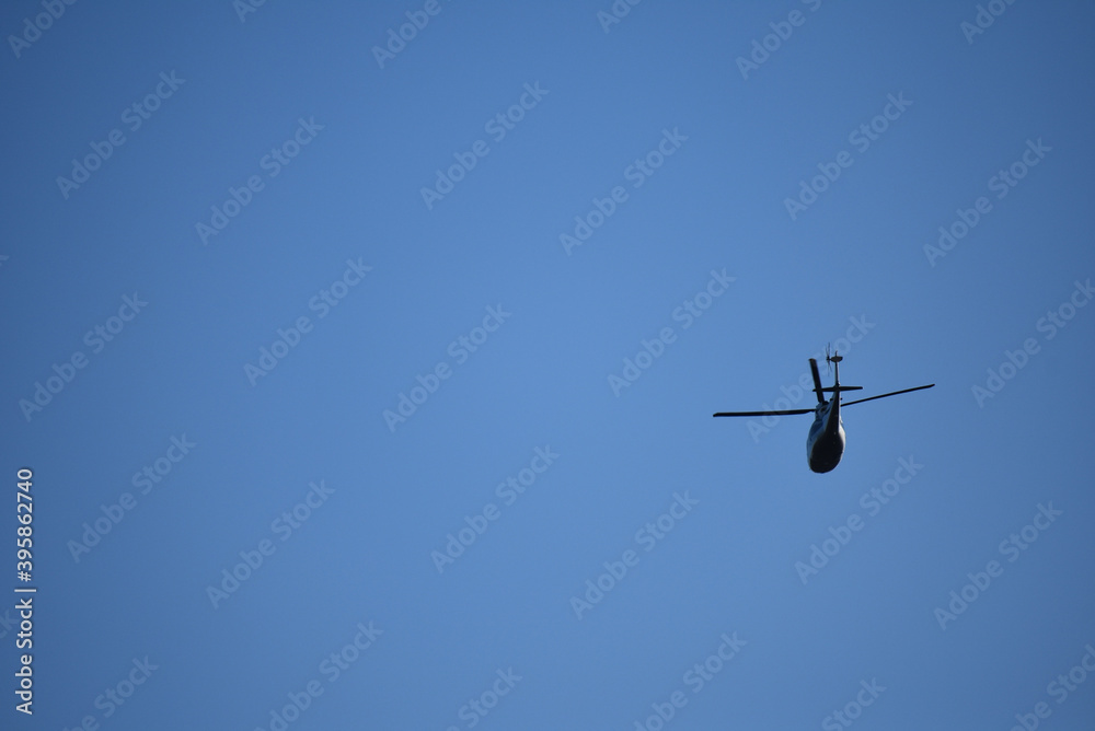 A helicopter flies overhead in Philadelphia in a blue sky. A helicopter flies overhead in Philadelphia in a blue sky.
