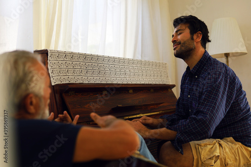 Family time father and son enjoy acoutic guitar and piano at home in holiday weekend. photo