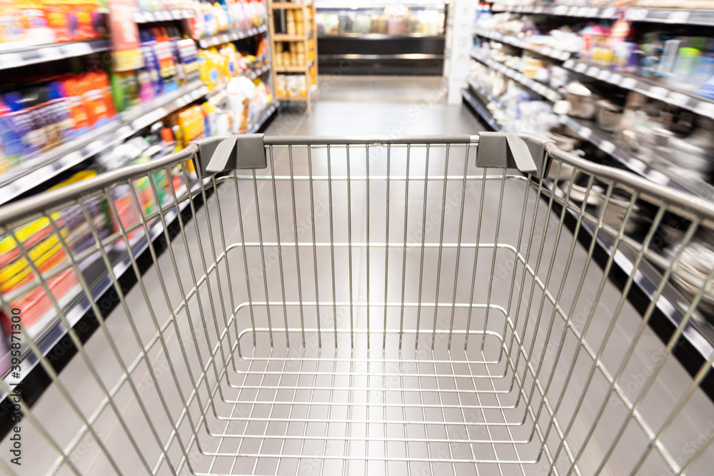 Shopping trolley cart moving in supermarket with motion blur aisle background Shopping trolley cart moving in supermarket with motion blur aisle background