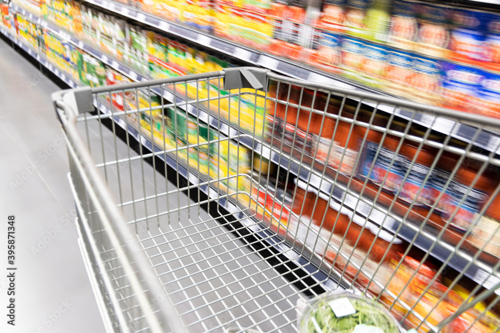 Shopping trolley cart moving in supermarket with motion blur aisle background Shopping trolley cart moving in supermarket with motion blur aisle background
