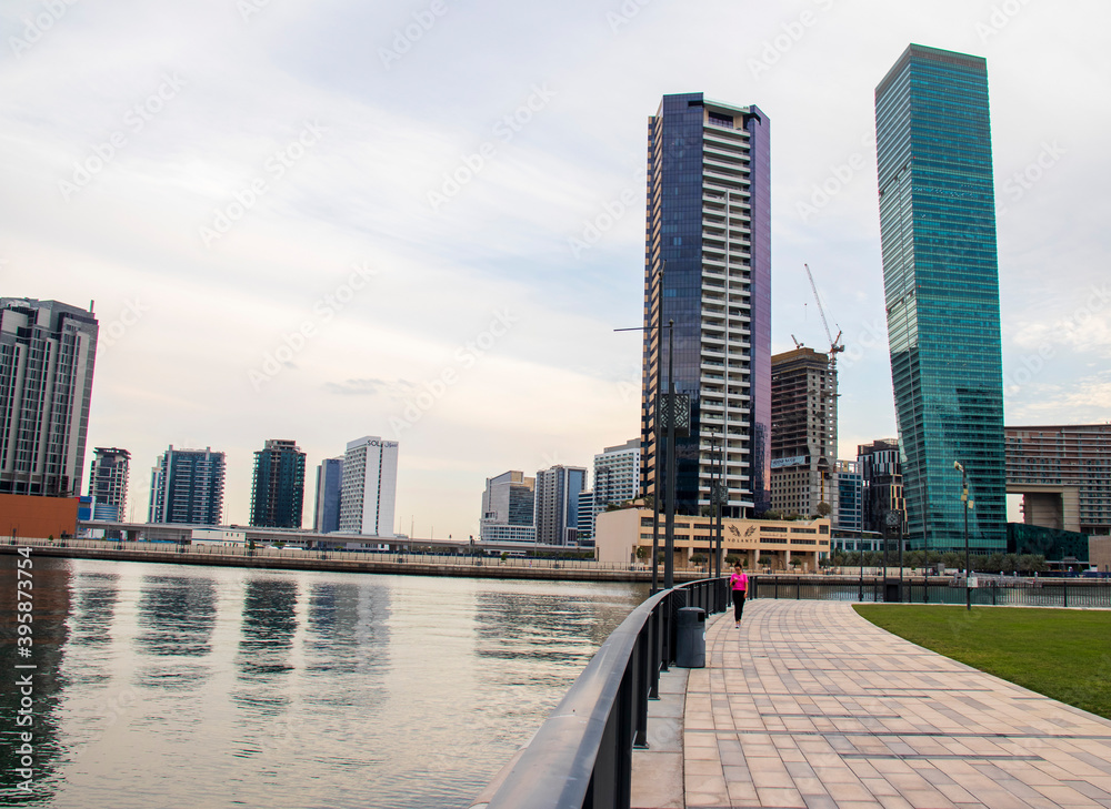 Obraz premium Young woman walking in the Dubai water canal area, business bay district. UAE.