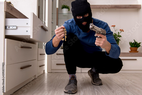 Male robber stealing valuable things from the house